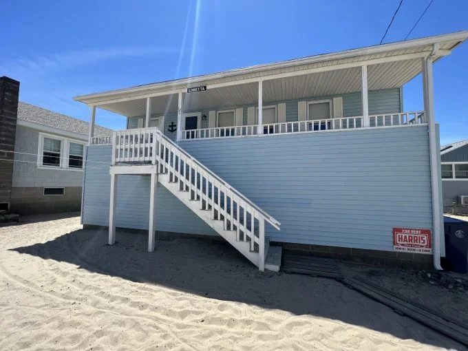 a beach house with a white staircase leading up to it.