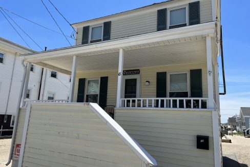 a white house with a porch and a white fence.