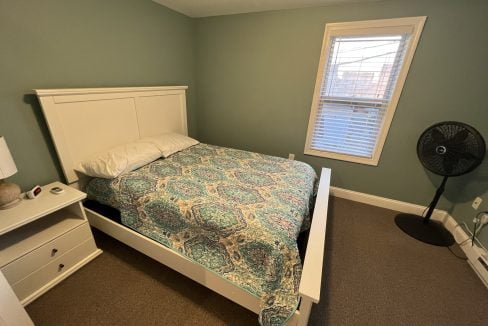 a bedroom with a bed and a fan.