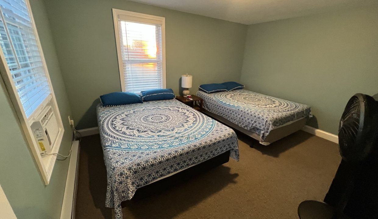 a couple of beds sitting in a bedroom next to a window.