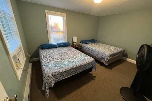 a couple of beds sitting in a bedroom next to a window.