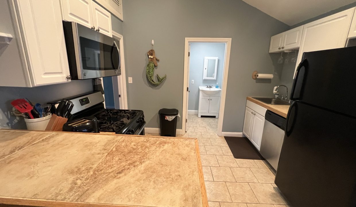 a kitchen with white cabinets and a black refrigerator.