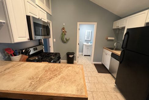 a kitchen with white cabinets and a black refrigerator.