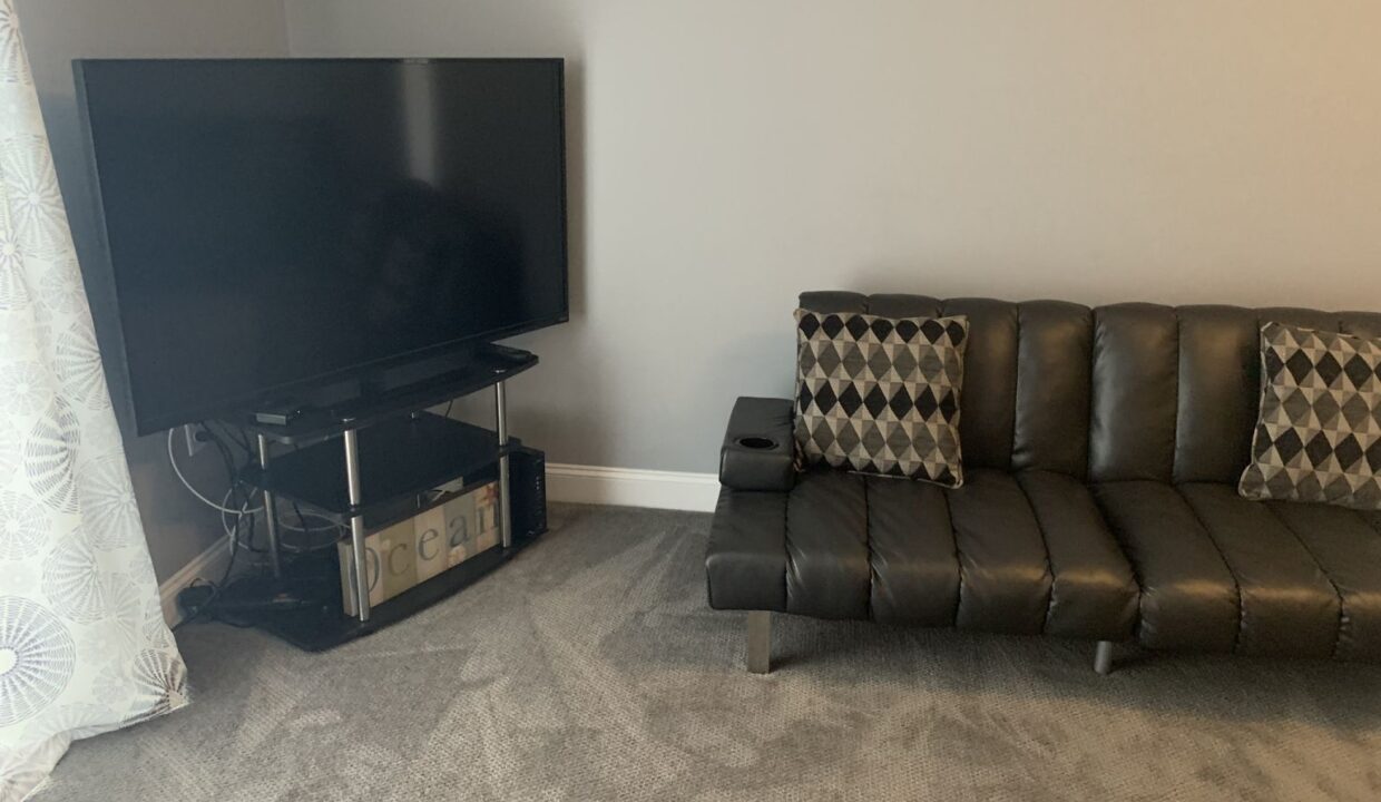 a living room with a black couch and a flat screen tv.