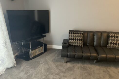 a living room with a black couch and a flat screen tv.