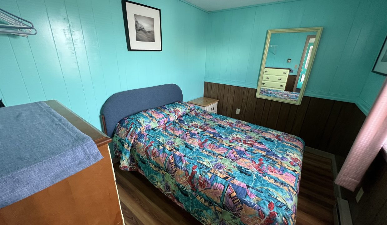 a bed room with a neatly made bed and a dresser.