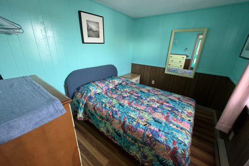 a bed room with a neatly made bed and a dresser.