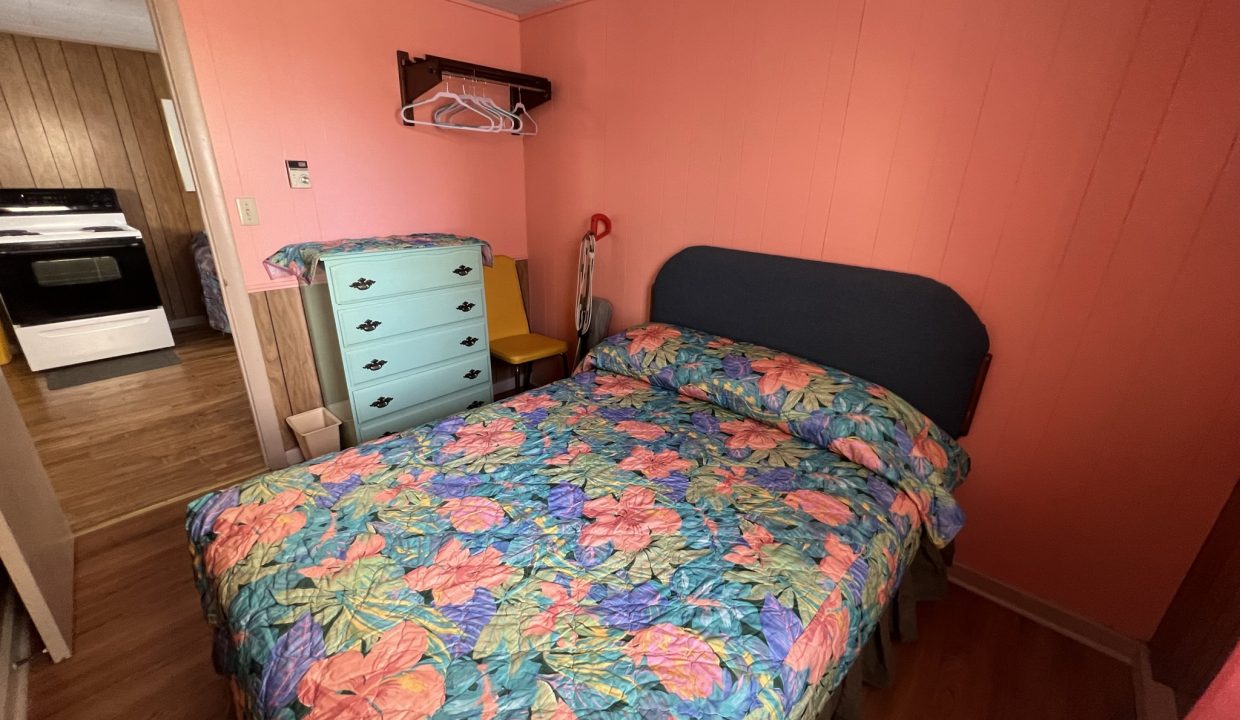 a bed room with a neatly made bed and a dresser.