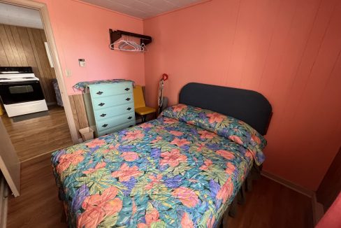 a bed room with a neatly made bed and a dresser.