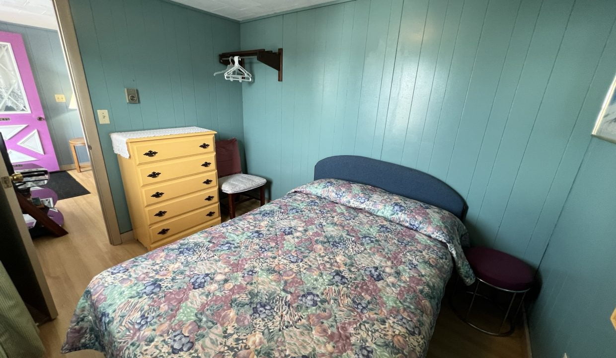 a bedroom with a bed, dresser, and mirror.