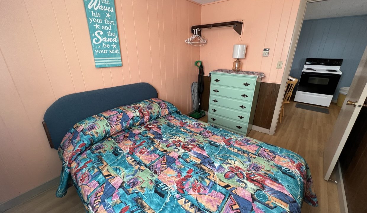 a bed room with a neatly made bed and a dresser.