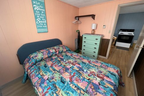 a bed room with a neatly made bed and a dresser.