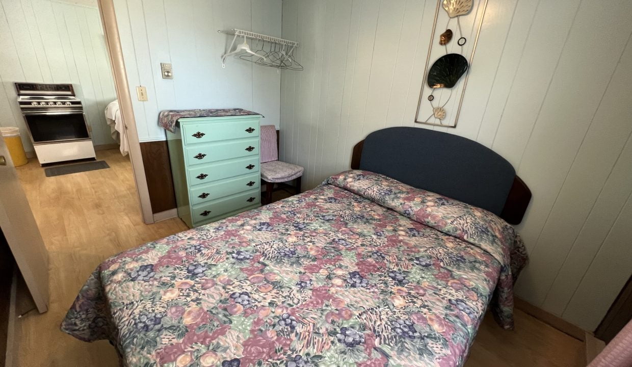 a bed room with a neatly made bed and a dresser.