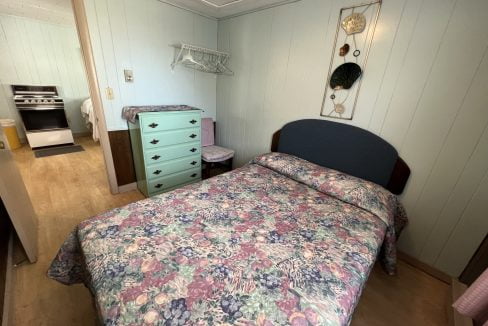 a bed room with a neatly made bed and a dresser.