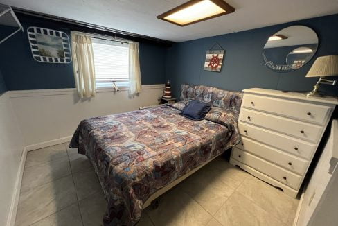 a bed room with a neatly made bed and a dresser.