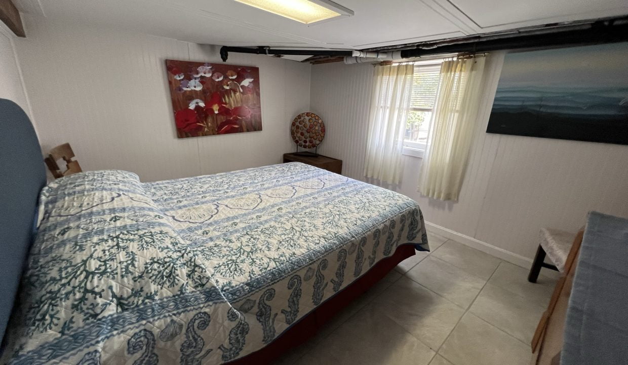 a bed room with a neatly made bed and a painting on the wall.