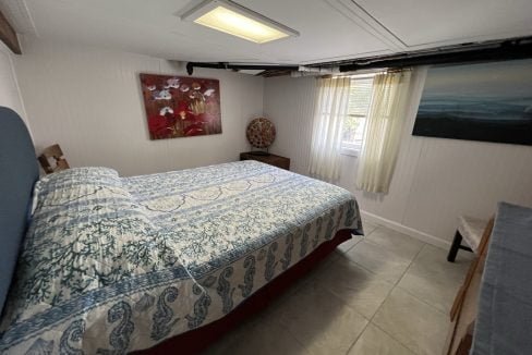 a bed room with a neatly made bed and a painting on the wall.