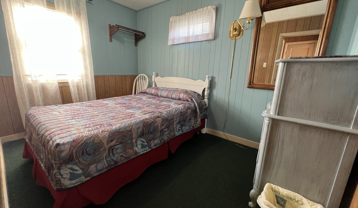 a bed room with a neatly made bed and a window.