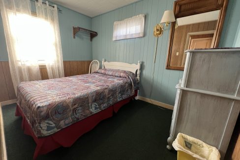 a bed room with a neatly made bed and a window.