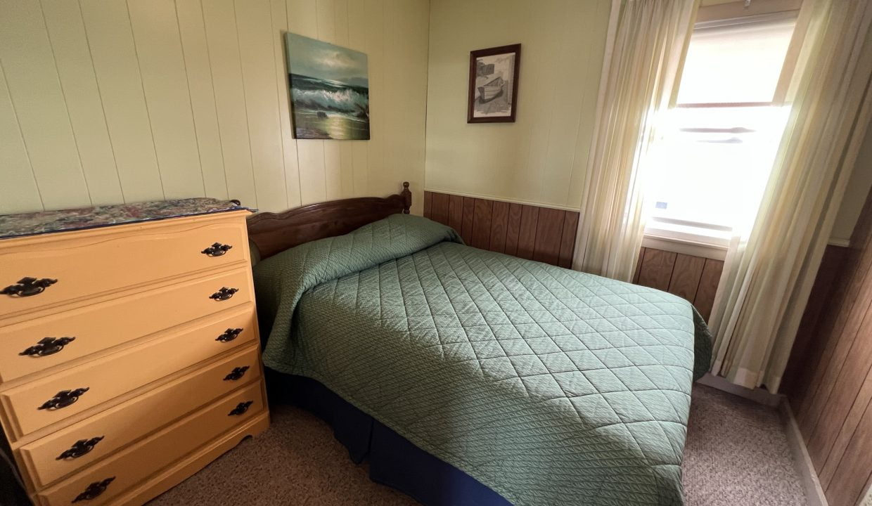 a bedroom with a bed, dresser and window.