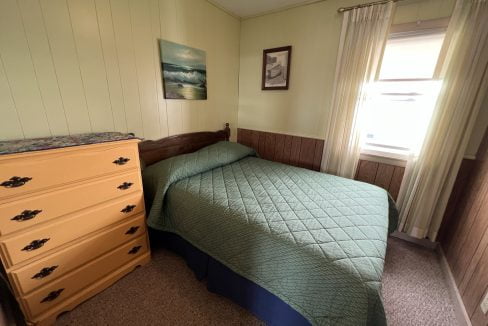 a bedroom with a bed, dresser and window.