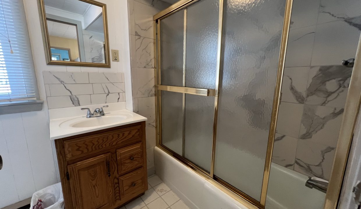 a bath room with a sink a mirror and a bath tub.