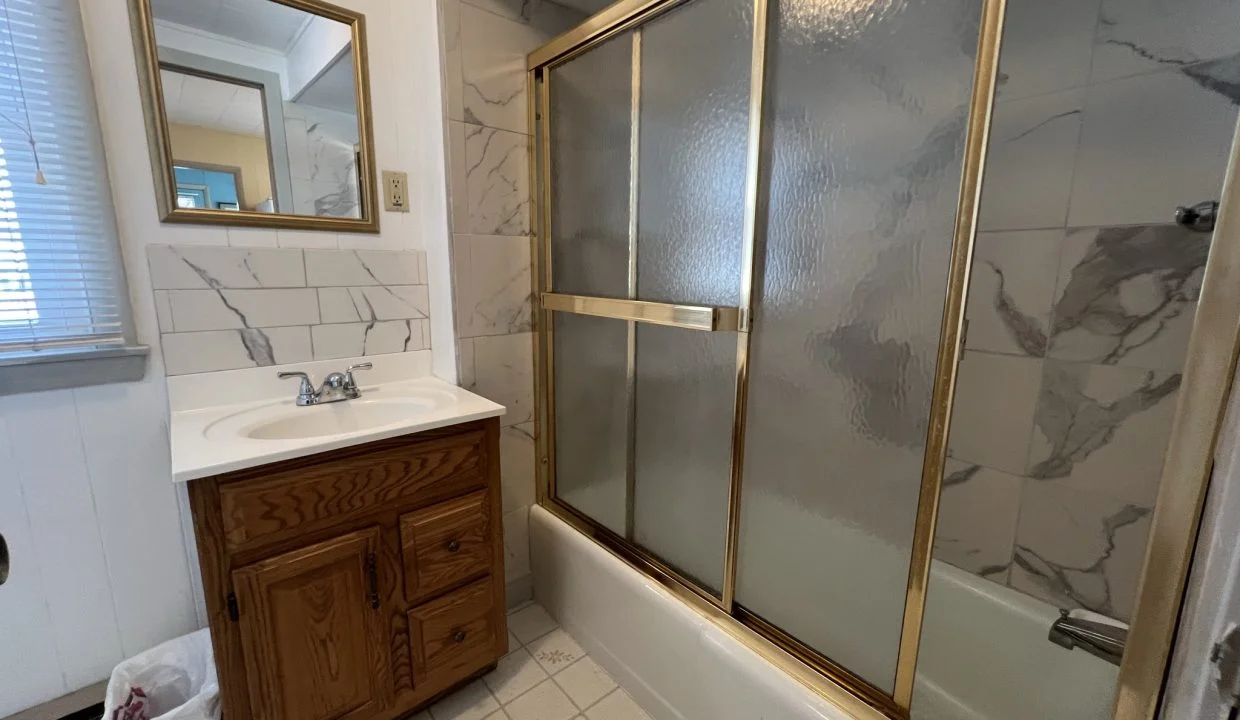a bath room with a sink a mirror and a bath tub.