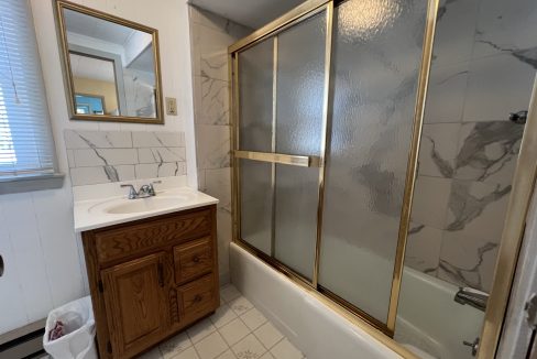 a bath room with a sink a mirror and a bath tub.