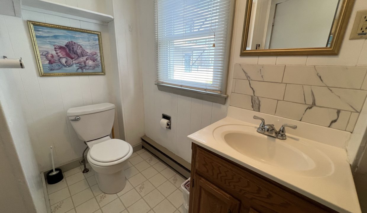 a bathroom with a toilet, sink, and mirror.