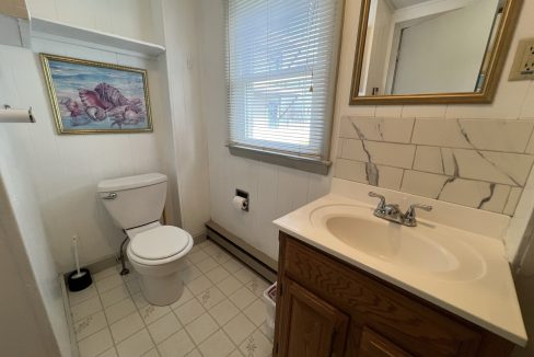 a bathroom with a toilet, sink, and mirror.