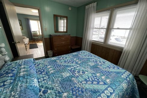 a bed room with a neatly made bed and a dresser.