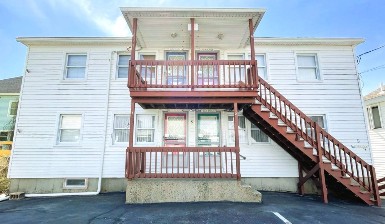 a two story apartment building with a red stair case.