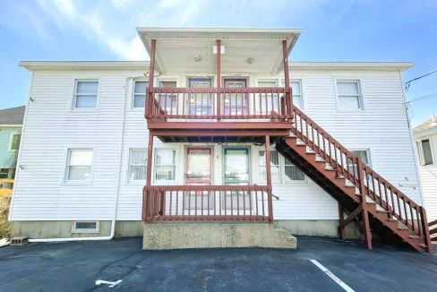 a two story apartment building with a red stair case.