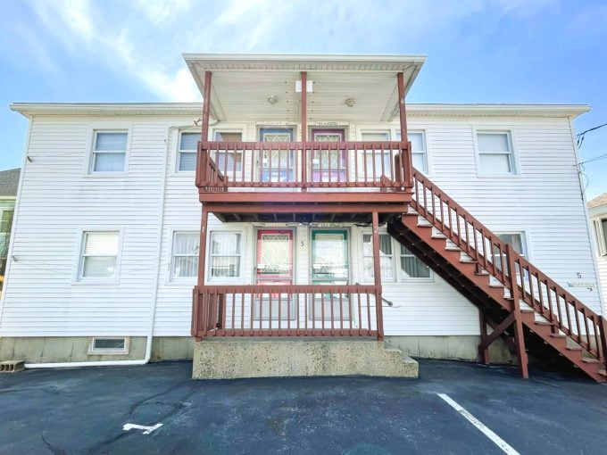 a two story apartment building with a red stair case.