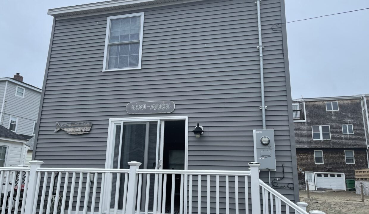 a gray house with a white porch and white railing.