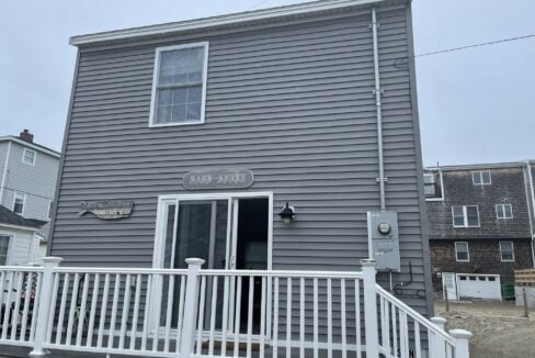 a gray house with a white porch and white railing.