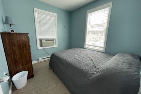 a bedroom with a bed and two windows.