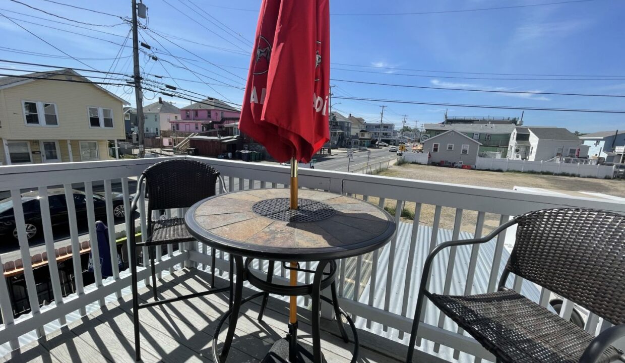 a table and chairs on a deck with an umbrella.