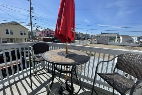 a table and chairs on a deck with an umbrella.