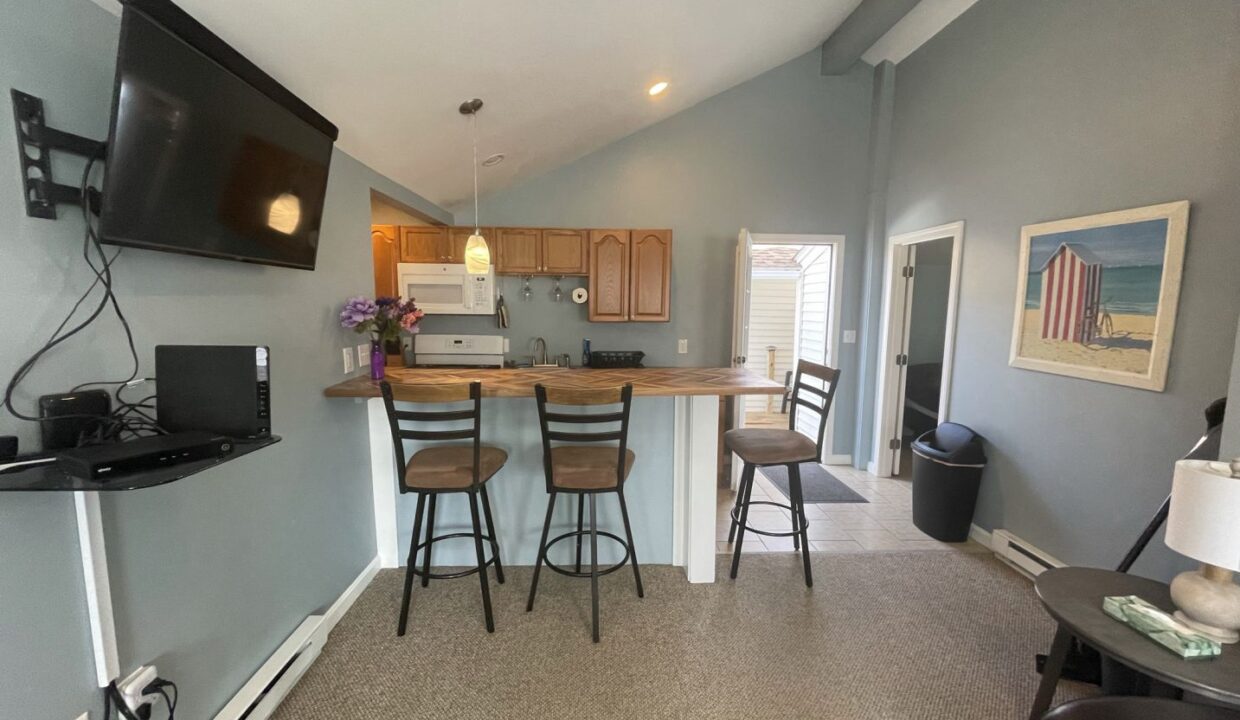 a kitchen with a bar and a television mounted on the wall.