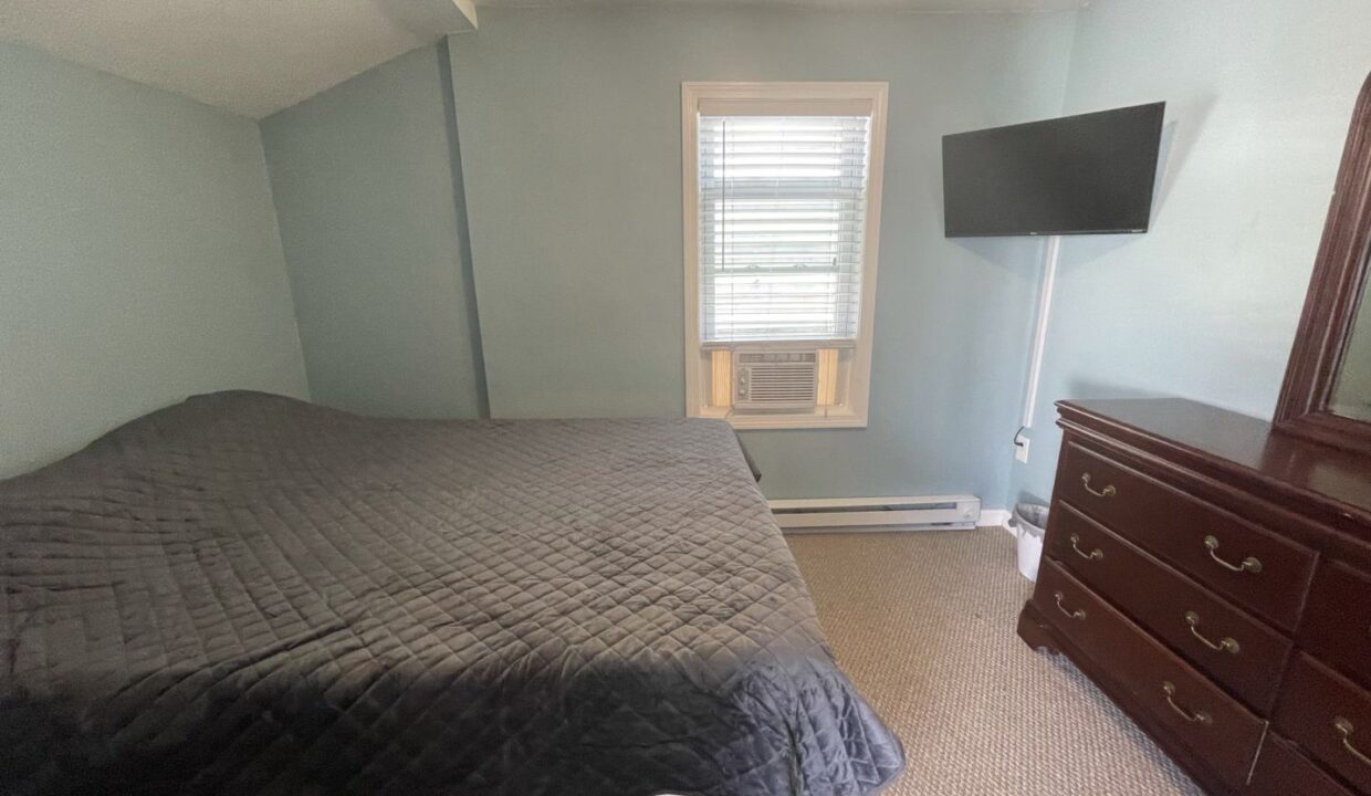 a bed room with a neatly made bed and a flat screen tv.