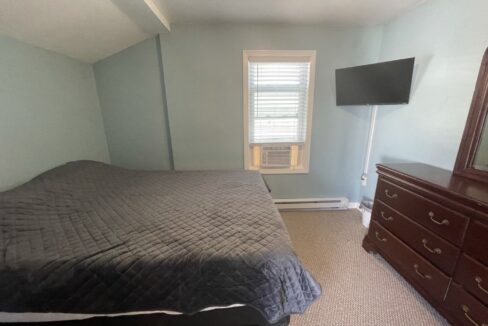 a bed room with a neatly made bed and a flat screen tv.