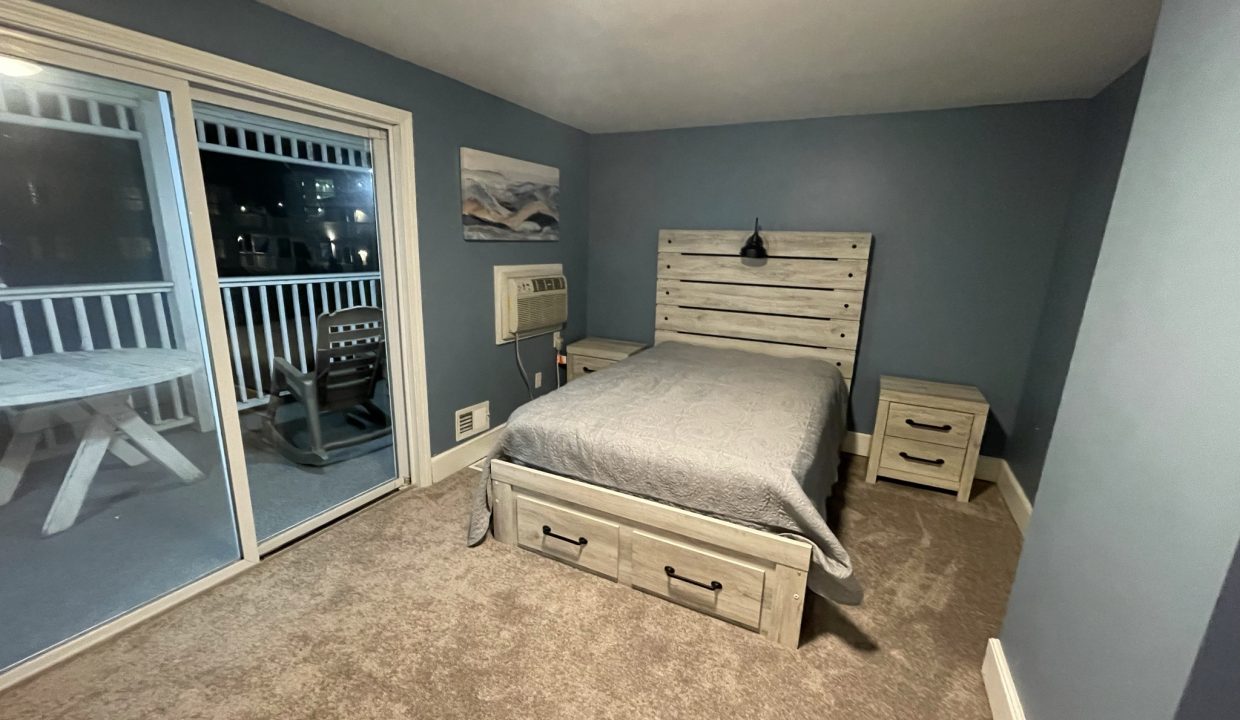 a bed room with a neatly made bed and a sliding glass door.