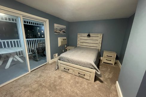 a bed room with a neatly made bed and a sliding glass door.