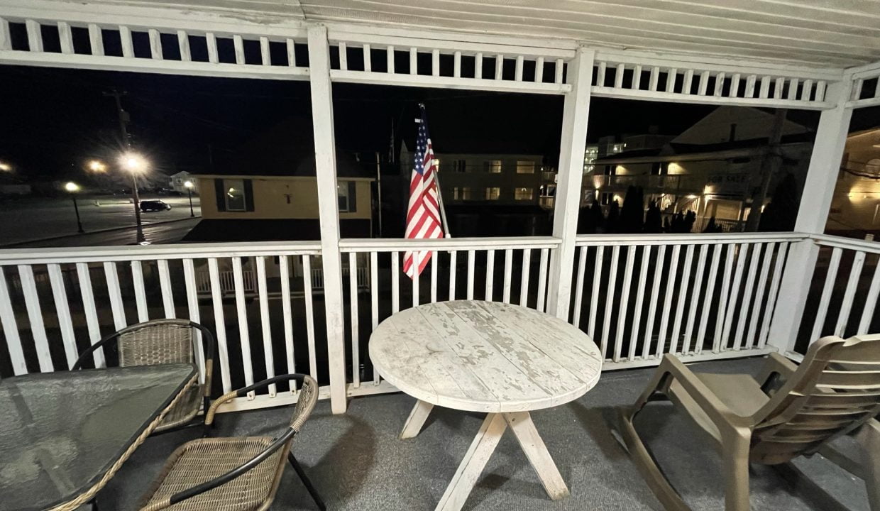a table and chairs on a porch at night.