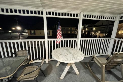 a table and chairs on a porch at night.