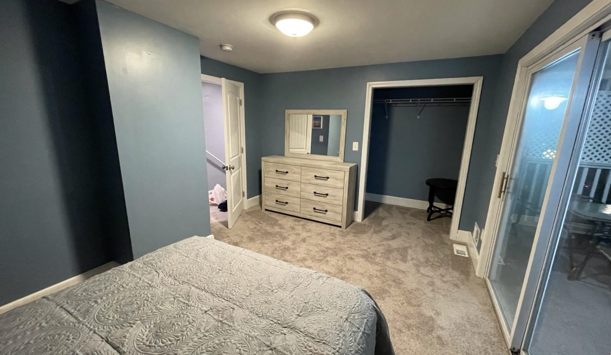 a bedroom with a bed, dresser, and sliding glass doors.