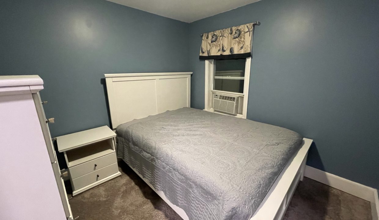 a bed room with a neatly made bed and a dresser.