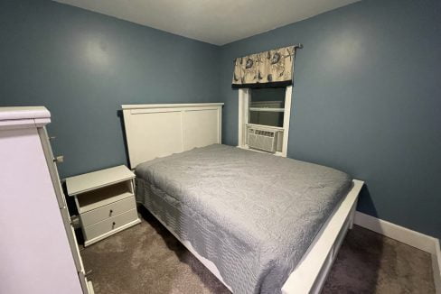 a bed room with a neatly made bed and a dresser.
