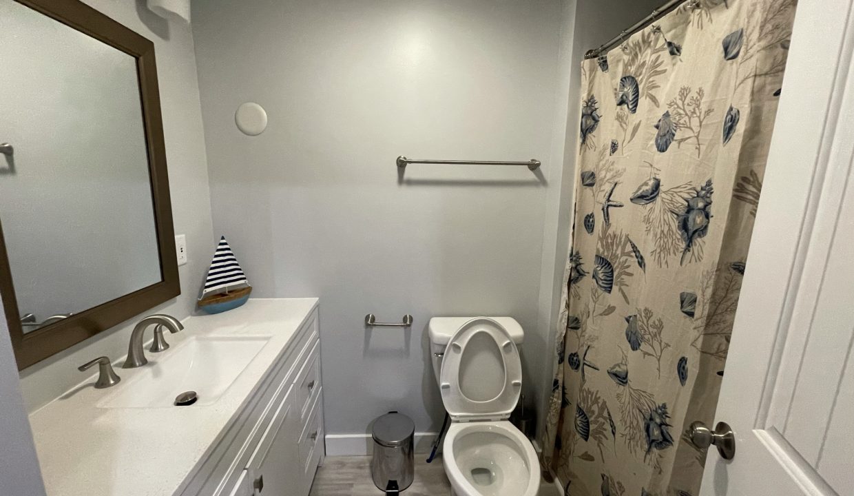 a bathroom with a toilet, sink, and shower.